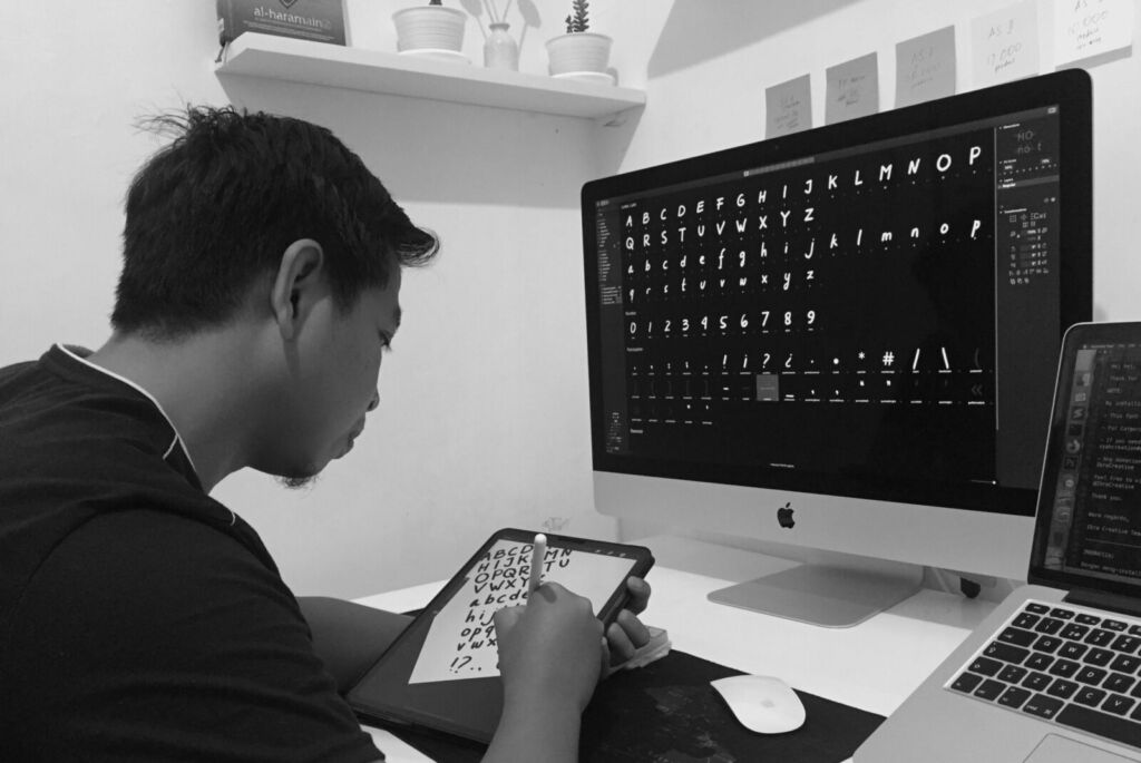 A designer at Ibra Creative Studio sketching letters on a tablet